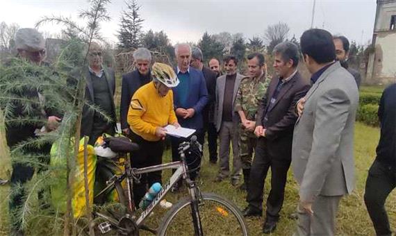 دوچرخه سوار گیلانی که برای کاشت نهال رکاب می زند